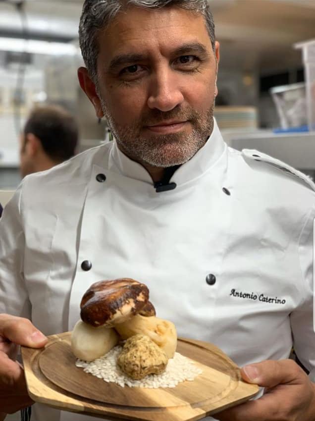 Chef Antonio in his whites, holding a plated dish
