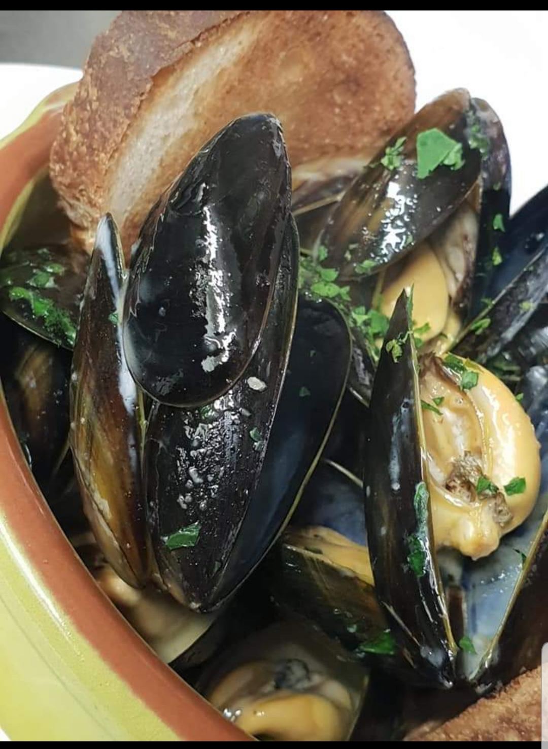 A bowl of mussels in a garlic and white wine broth